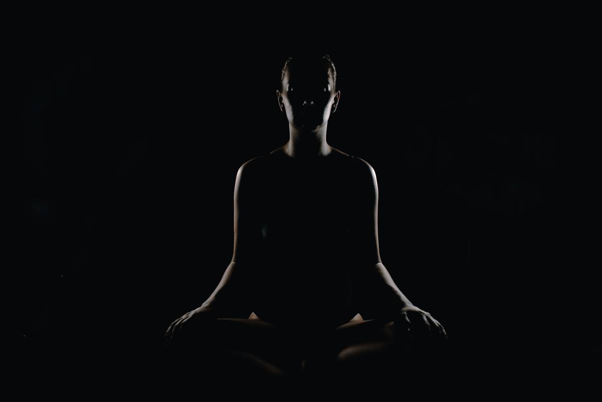 Woman sitting comfortably on a cushion practicing simple meditation techniques with eyes closed and hands resting on knees