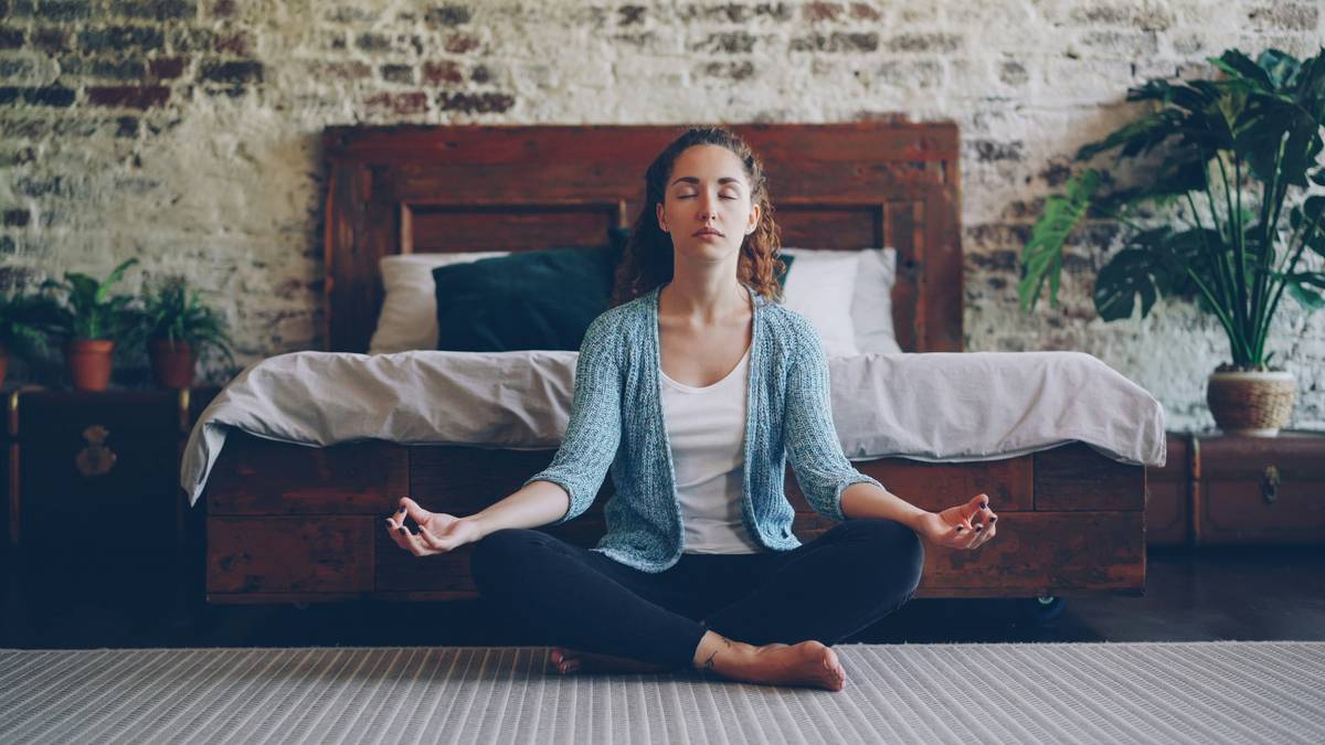 Woman practicing daily mindfulness practice while sitting comfortably on a cushion near a window with soft natural light